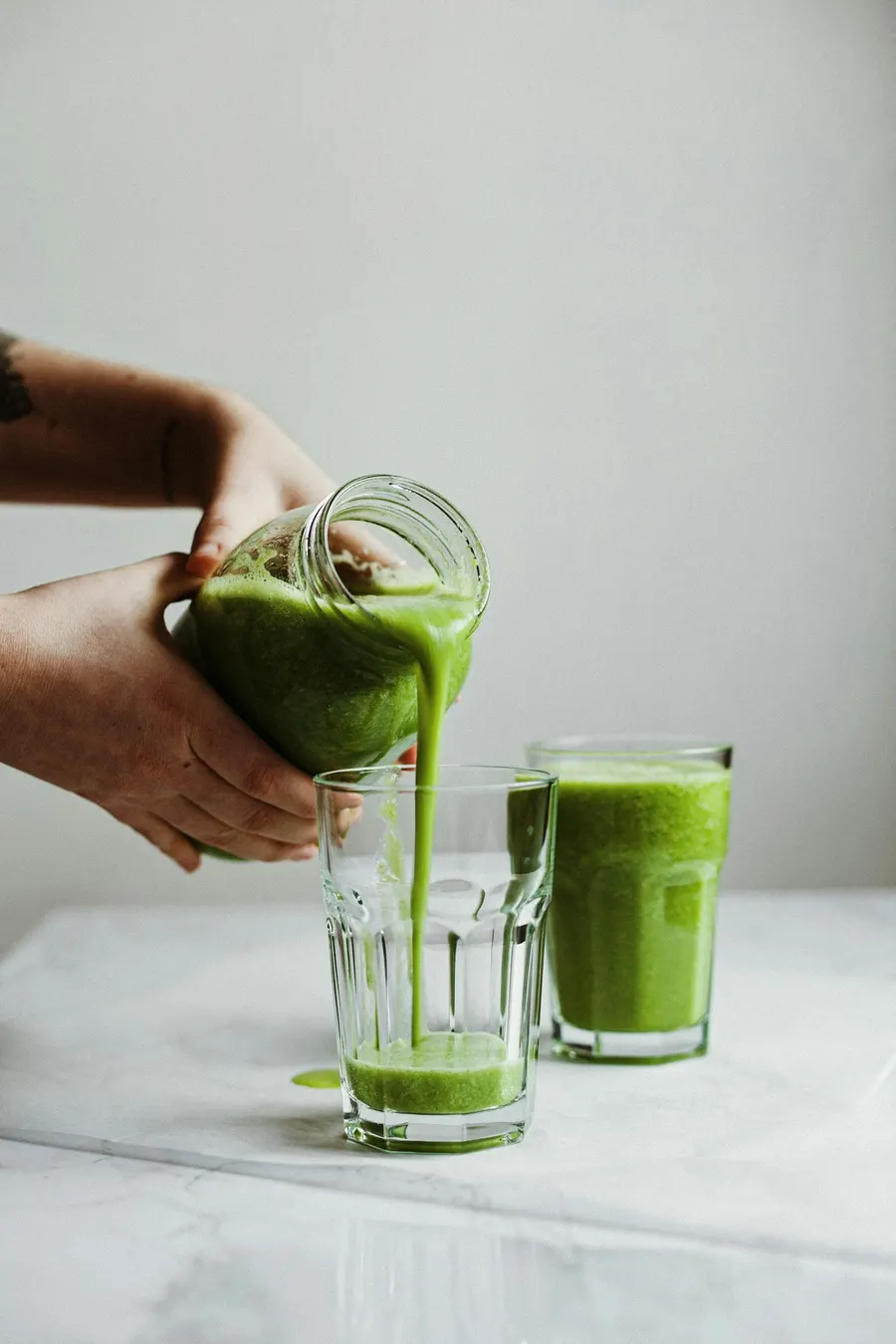Fresh green juice being poured into a glass