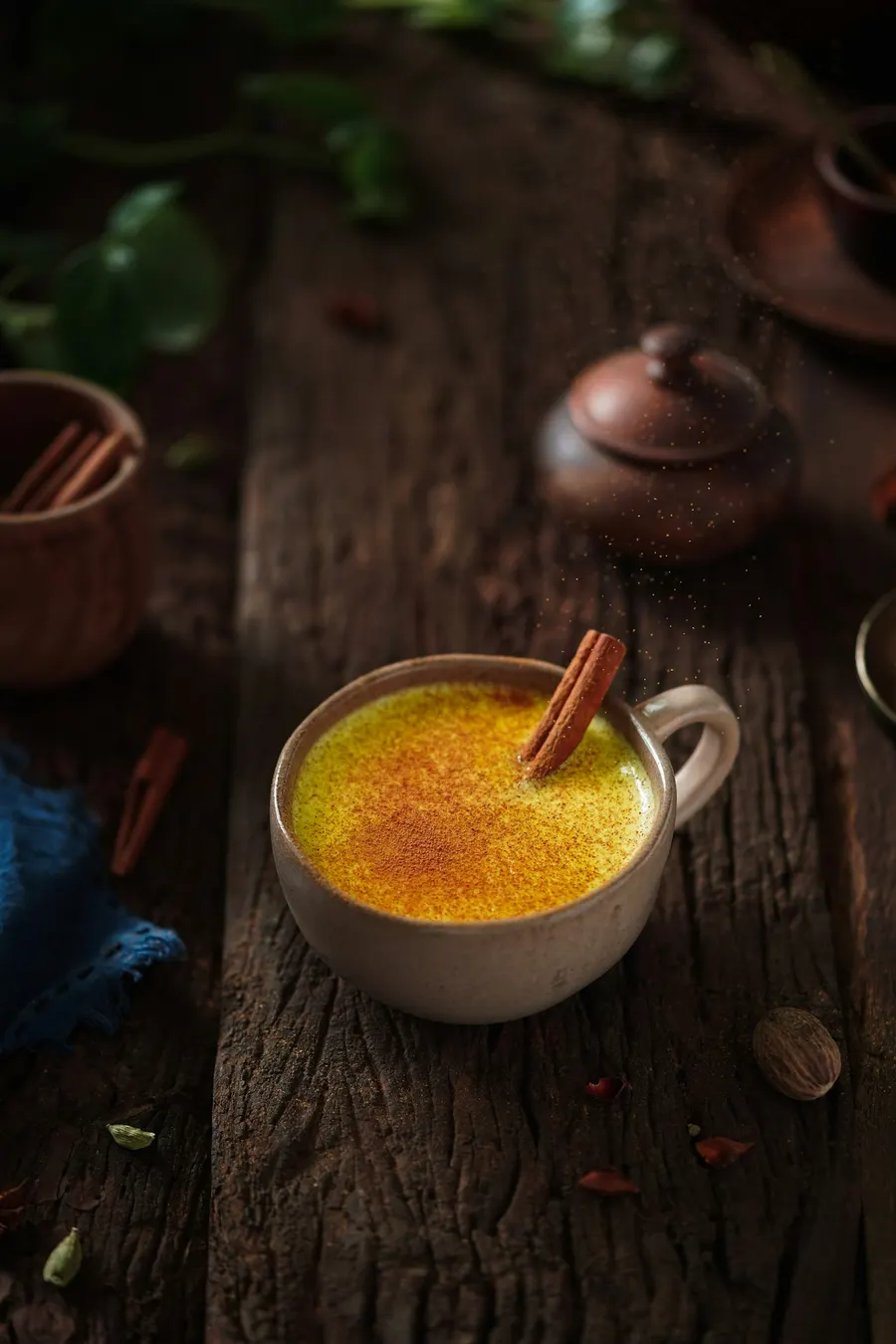 A cup of warm golden turmeric milk with a cinnamon stick